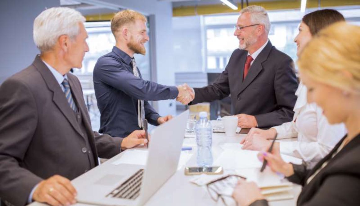 businesspeople-looking-two-businessmen-shaking-hands-business-meeting_800x600