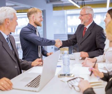 businesspeople-looking-two-businessmen-shaking-hands-business-meeting_800x600