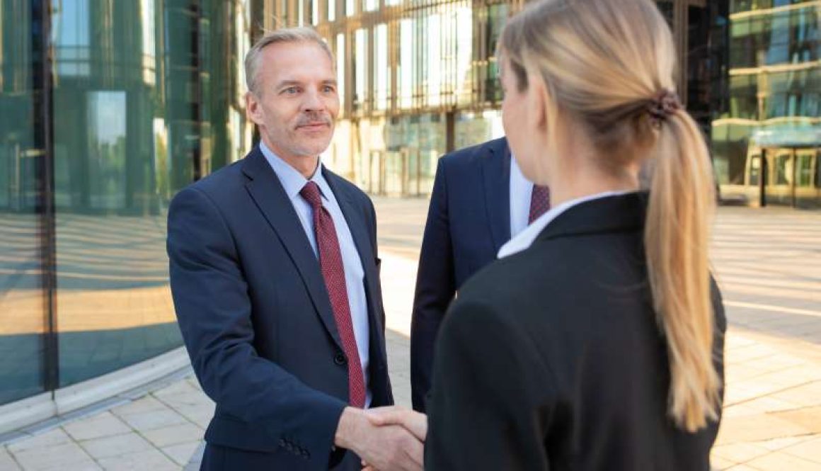 confident-business-partners-standing-near-office-buildings-shaking-hands-meeting-talking-city-contract-discussion-partnership-concept_800x600