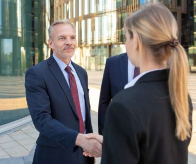confident-business-partners-standing-near-office-buildings-shaking-hands-meeting-talking-city-contract-discussion-partnership-concept_800x600