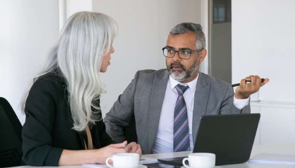 couple-serious-colleagues-sitting-table-with-laptop-documents-cups-coffee-talking-medium-shot-teamwork-communication-concept_800x600