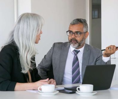 couple-serious-colleagues-sitting-table-with-laptop-documents-cups-coffee-talking-medium-shot-teamwork-communication-concept_800x600