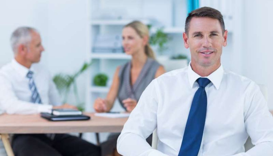 happy-businessman-smiling-camera-with-colleagues_800x600