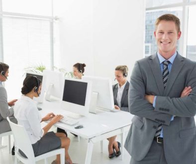smiling-manager-standing-arms-crossed-with-staff_800x600