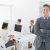 smiling-manager-standing-arms-crossed-with-staff_800x600