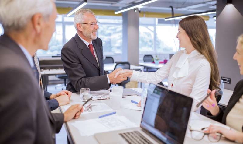 smiling-senior-man-shaking-hands-with-young-businesswoman-office_800x600