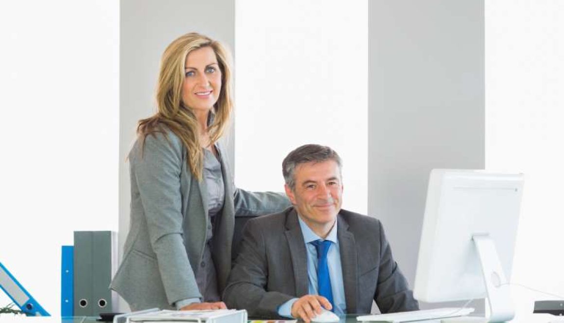 two-joyful-businesspeople-looking-camera-using-computer_800x600