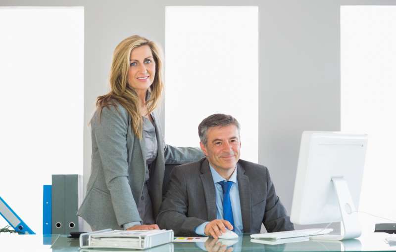 two-joyful-businesspeople-looking-camera-using-computer_800x600